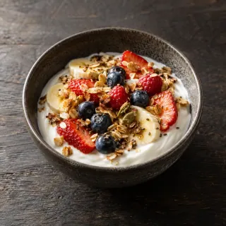 A bowl of natural yogurt with seasonal fresh fruit and toasted grains