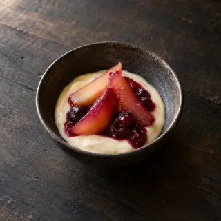 A small bowl of softly set vanilla cream with seasonal poached fruit and a little fruit compote