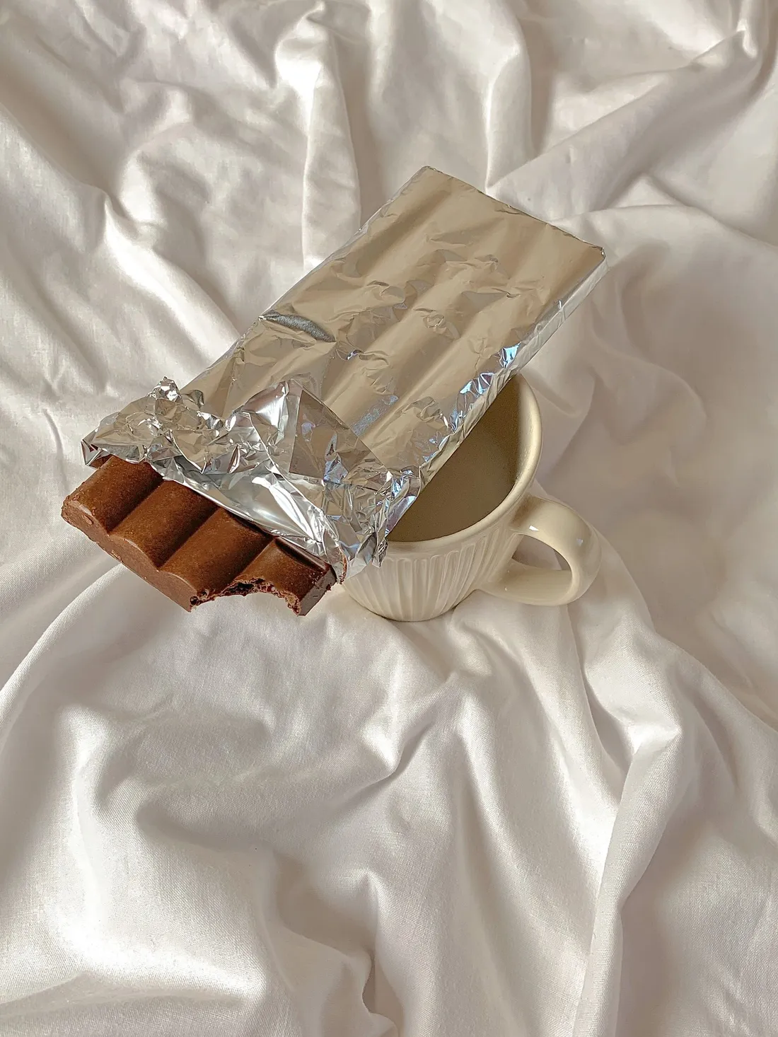 Chocolate wrapped in aluminum foil on a ceramic cup