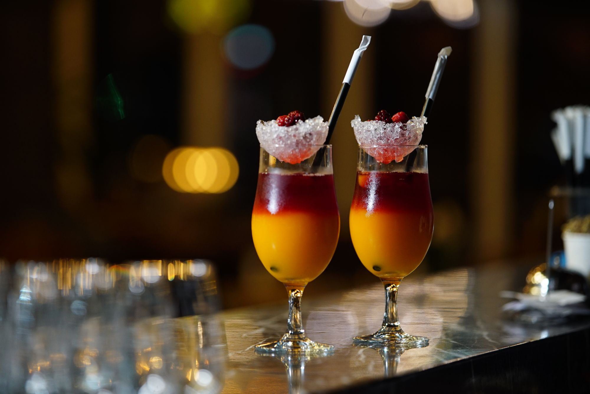 Two colorful cocktails on a restaurant bar