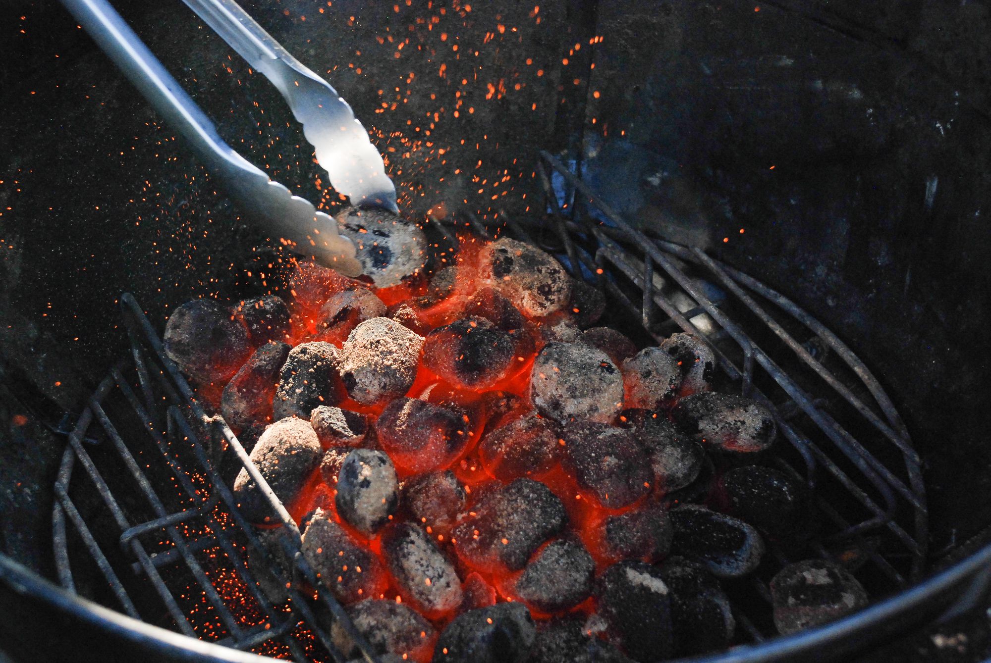 Glowing charcoal and tongs in a grill