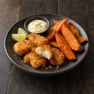 A small plate of golden crumbed fish bites, sweet potato wedges and a little lime mayonnaise