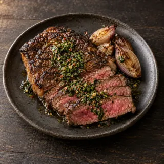 A cooked grilled steak, partly sliced to show a natural rosy interior, Sichuan chimichurri and roasted shallot
