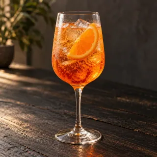 A bright amber-orange mandarin aperitif and sparkling-wine spritz in a plain stemmed wine glass with realistic ice and a mandarin slice