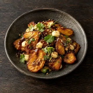 Crisp fried plantain slices with tamarind dressing, small dots of yuzu crema and coriander