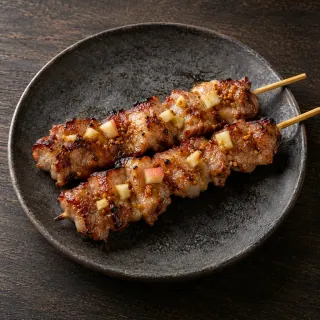 Two bamboo skewers of grilled pork collar pieces with miso adobo, a little apple and mustard seed