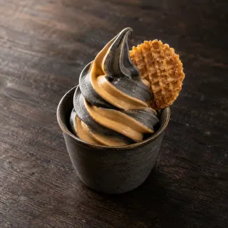 A small cup of naturally swirled black sesame and dulce de leche soft serve, one crisp wafer