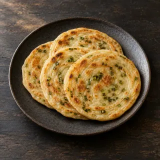 Four thin warm round flatbreads with scallion oil, slightly overlapping