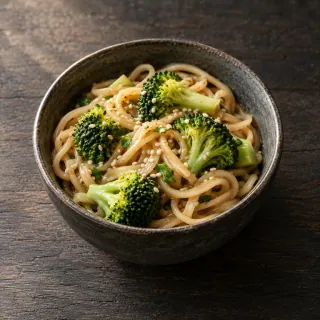 A small bowl of soft noodles, broccoli and light sesame sauce
