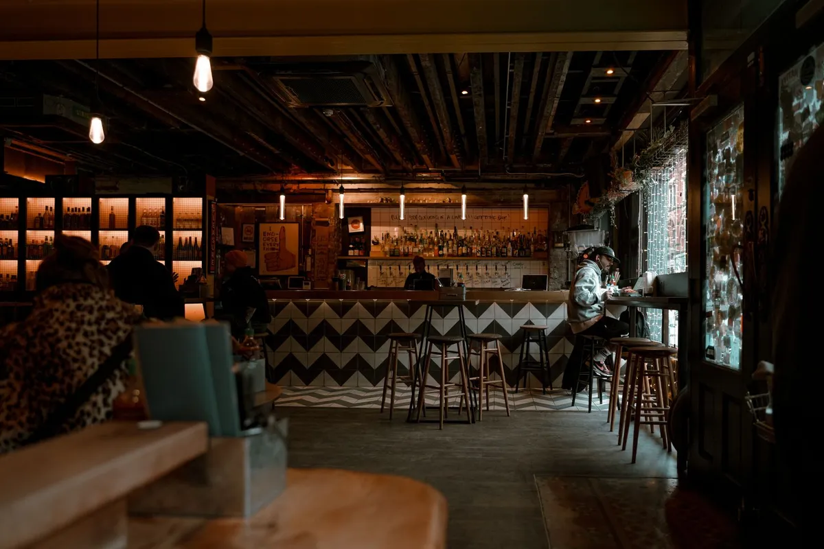 A dimly lit bar interior with chevron-tiled counter and shelves of bottles