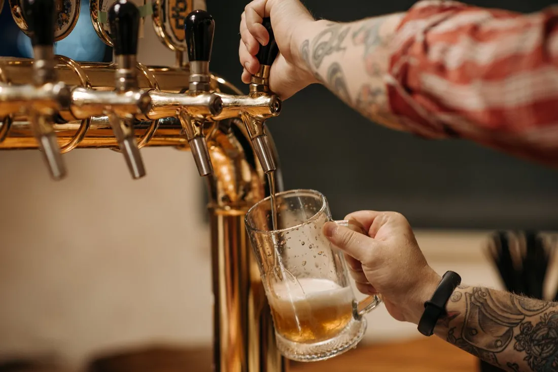 Beer being poured into a glass beneath a row of taps