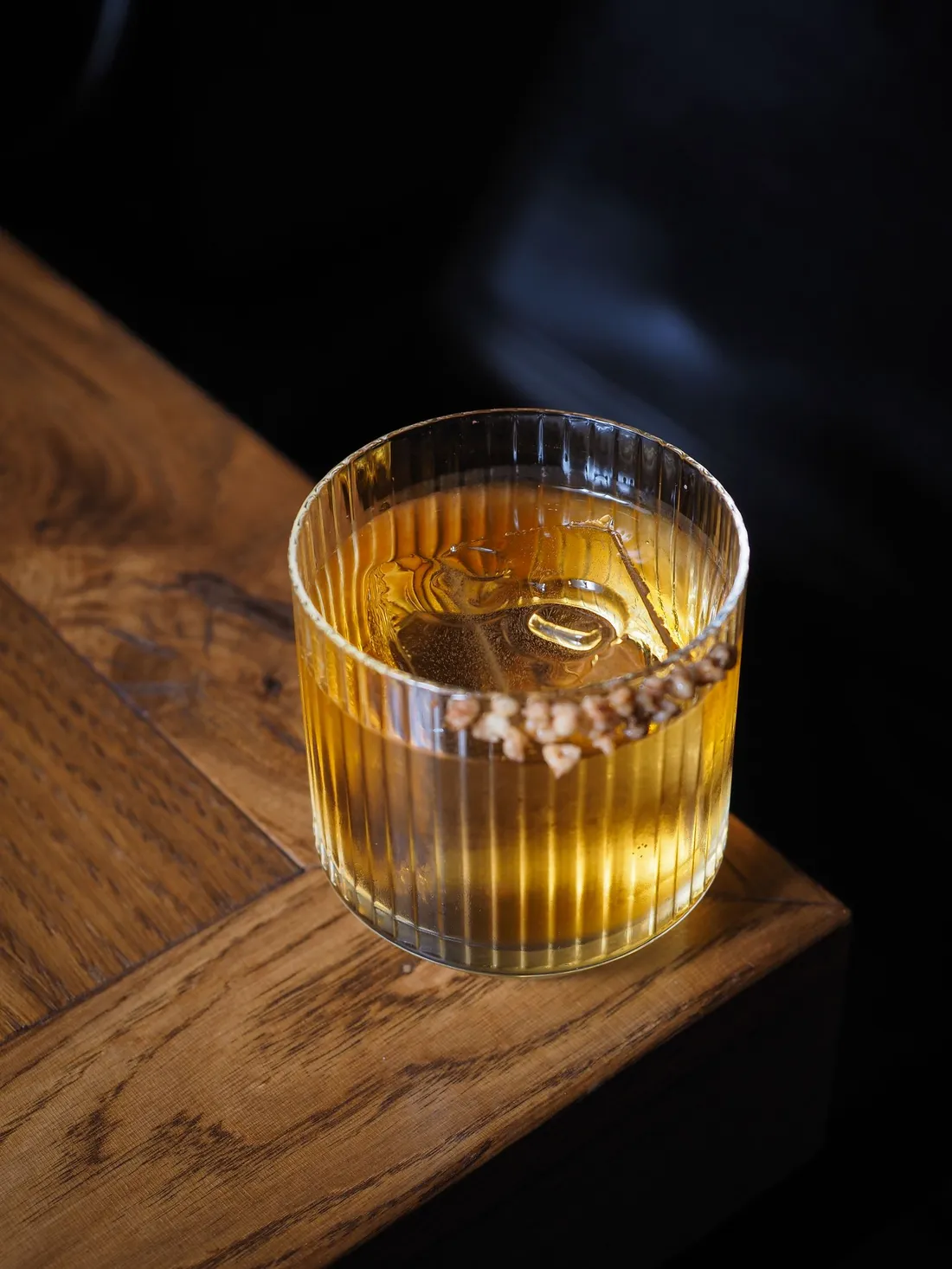 A glass of whisky catching warm light on a wooden table