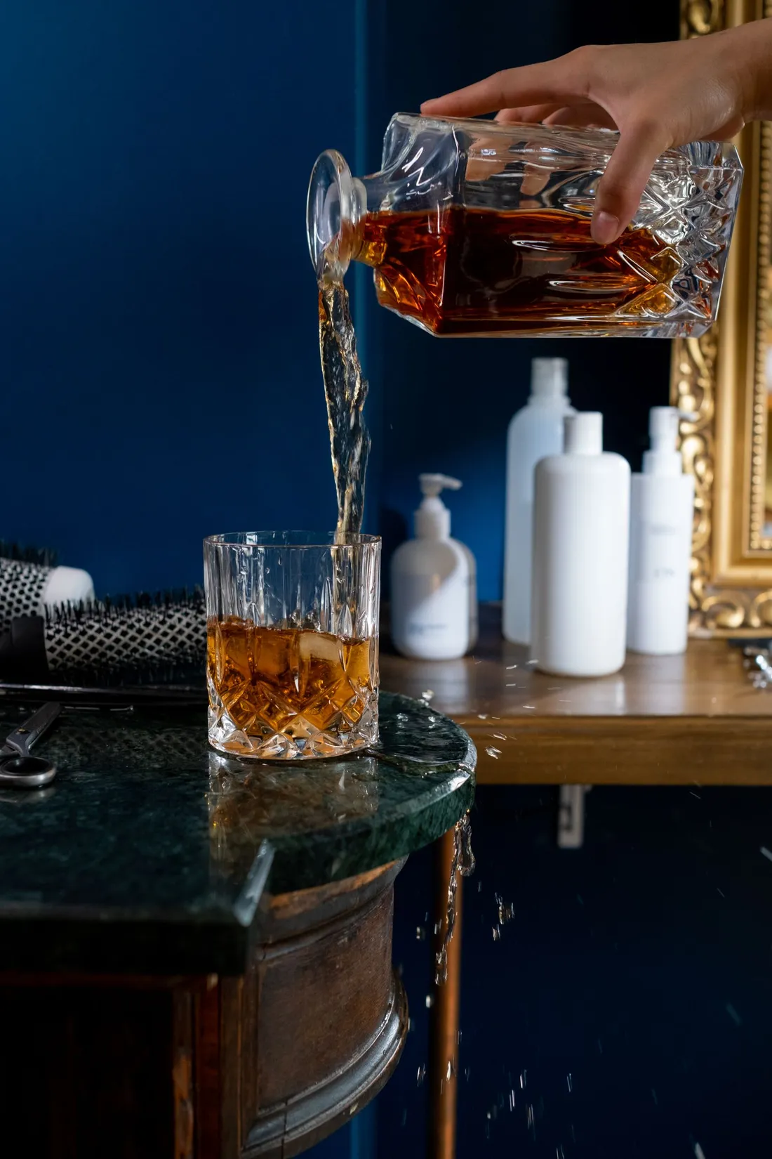 Whisky being poured from a decanter into a glass with ice