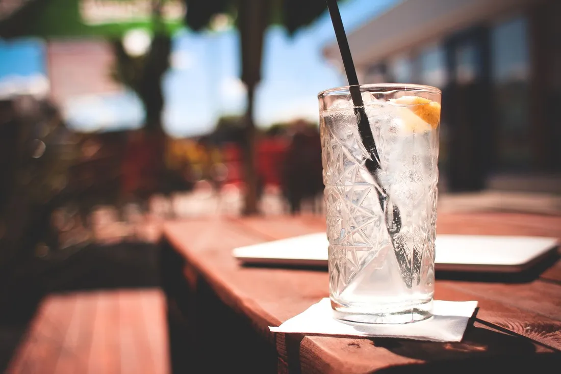 A gin and tonic with ice on an outdoor café table