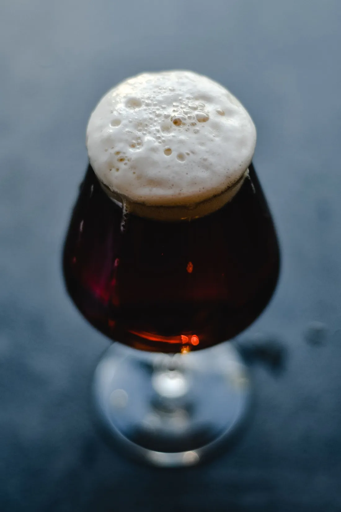 A snifter glass of deep amber beer catching the light
