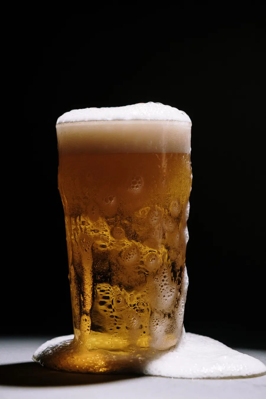 An overflowing glass of golden lager