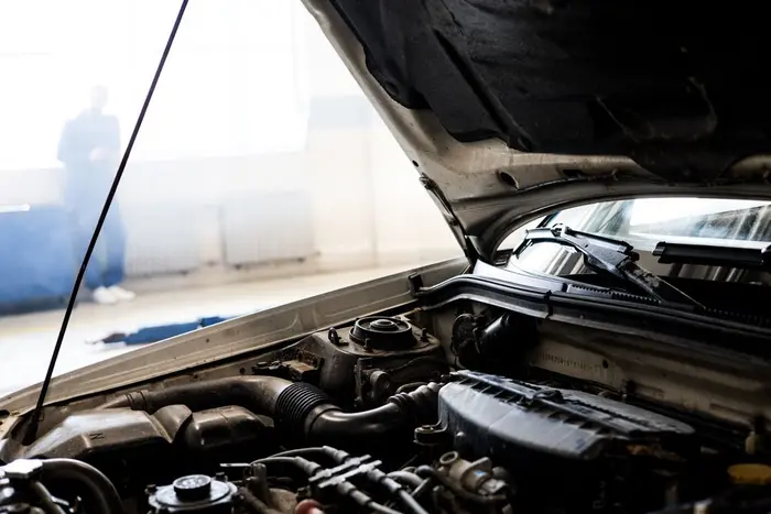 A car with the hood open in an indoor garage, ready for a parts inspection