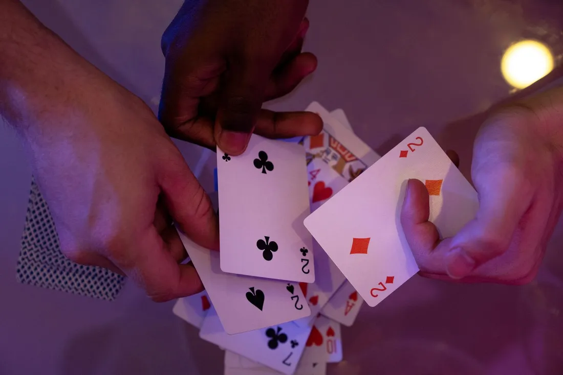 Hands holding a set of playing cards at a table