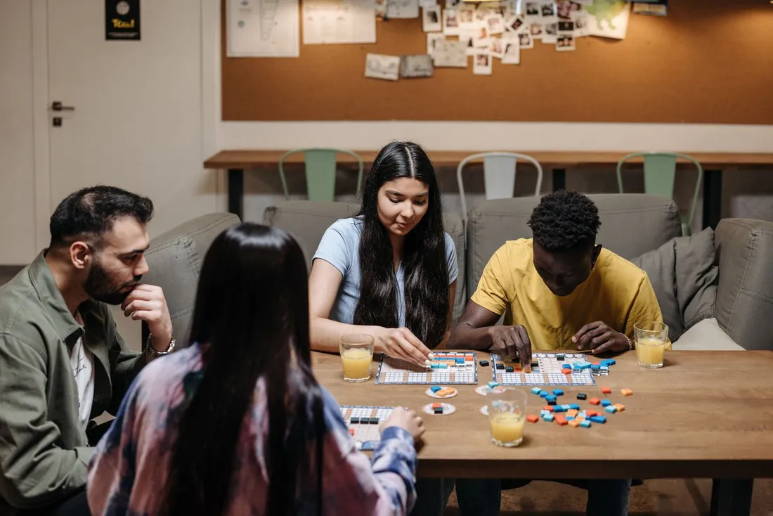 People sitting at a wooden table playing a board game