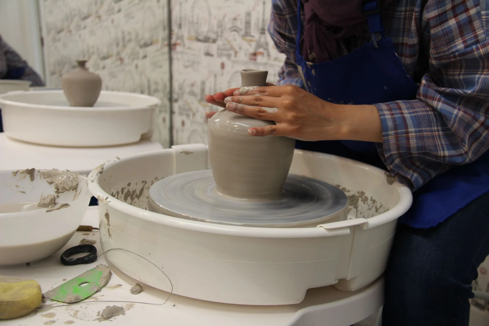 Potter's hands working clay on the wheel