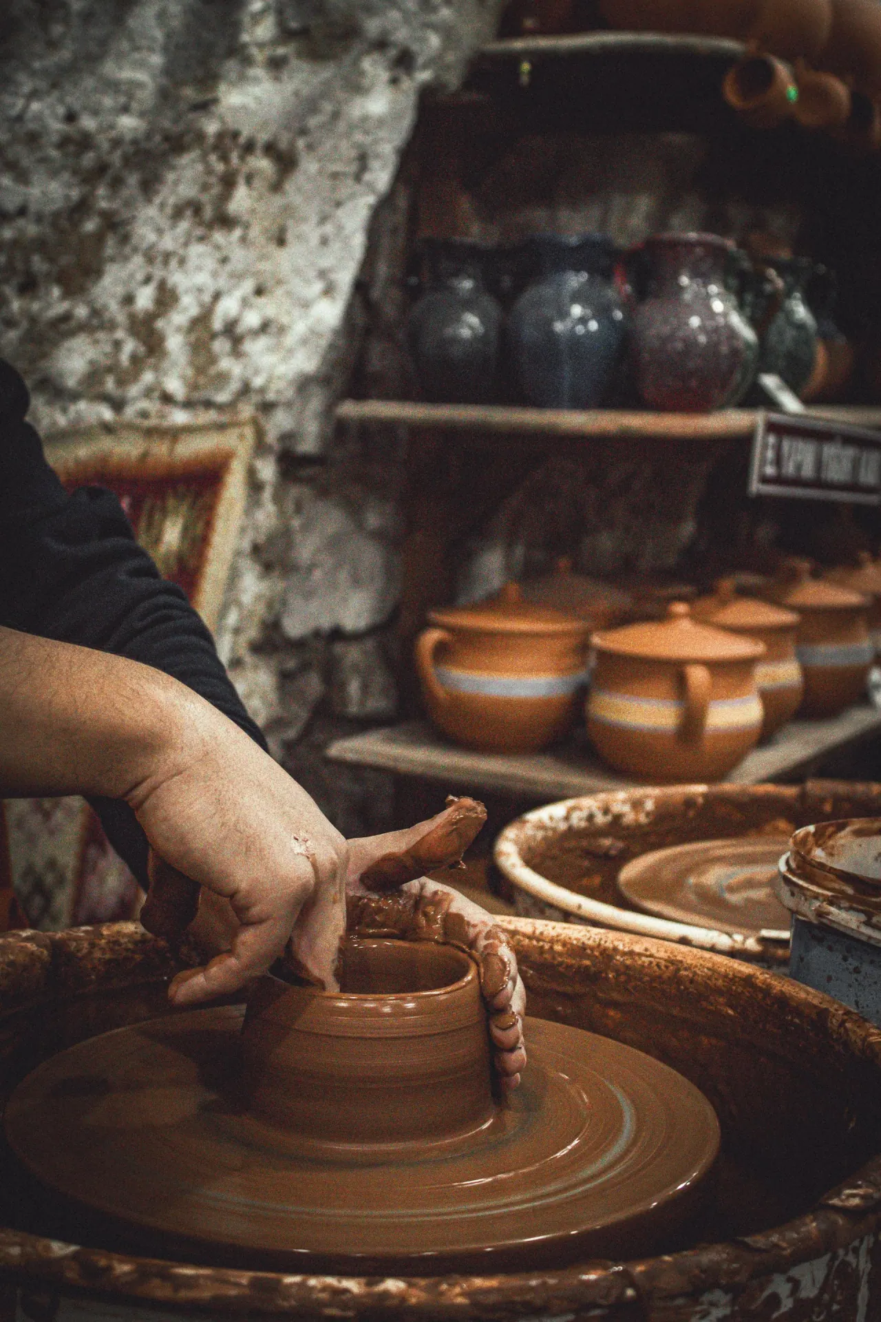 A potter shaping clay by hand on a spinning wheel