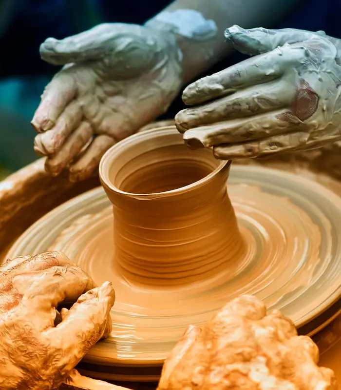Hands forming clay on a pottery wheel