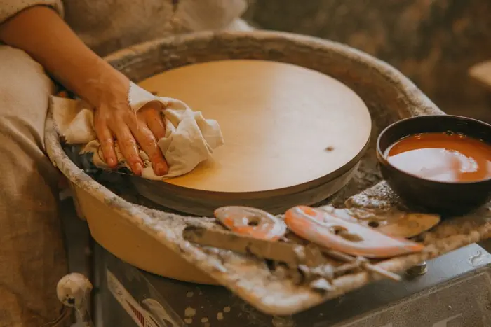 A potter's tools and glaze bowl beside a wheel