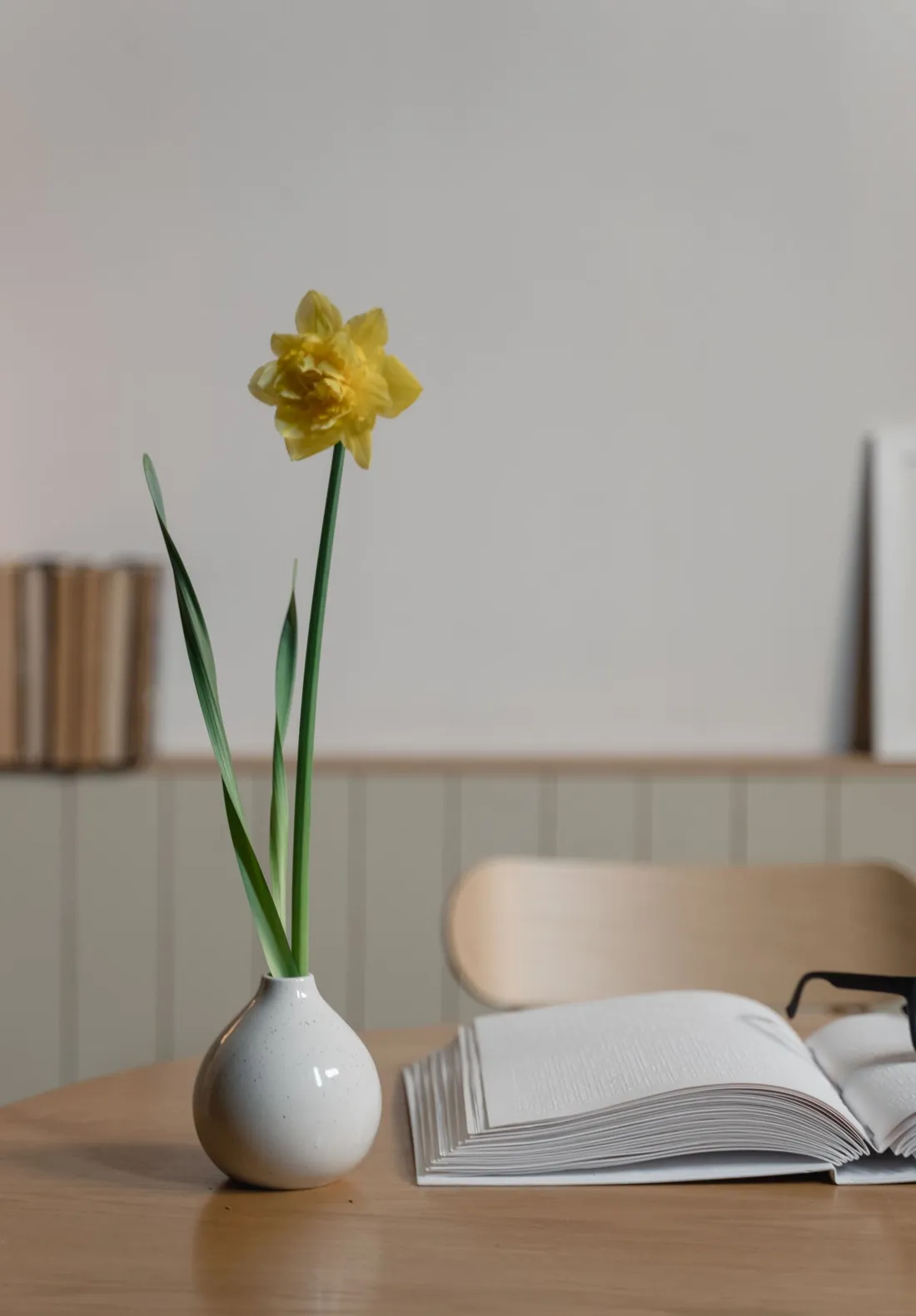 A yellow flower in a white ceramic vase