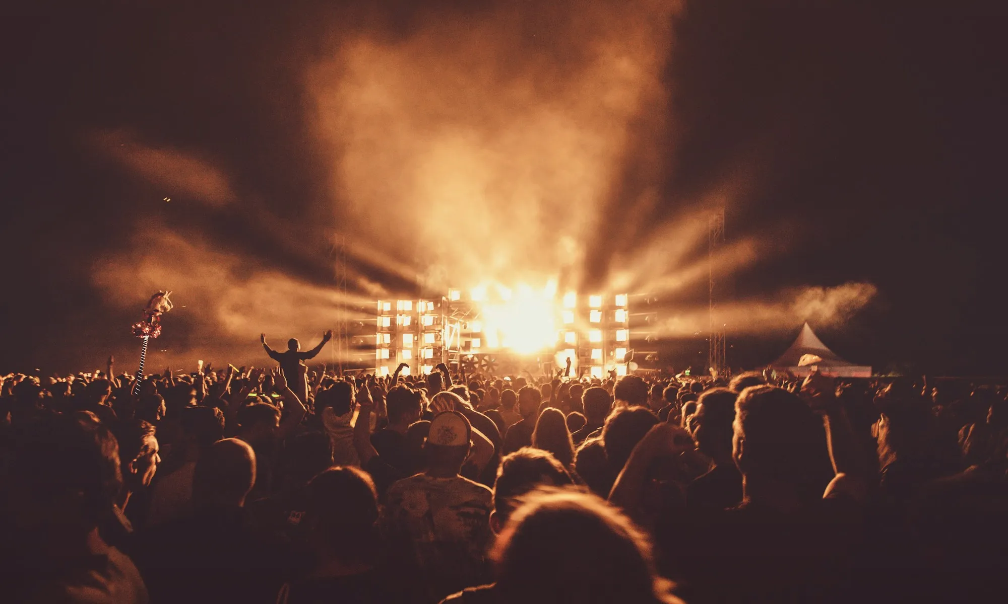Festival crowd at dusk with the stage alight