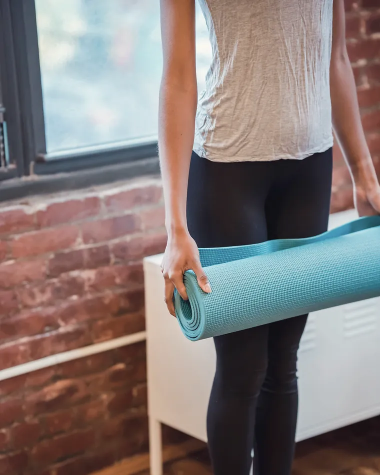 A student at the top of the stairs with a rolled mat, about to come in