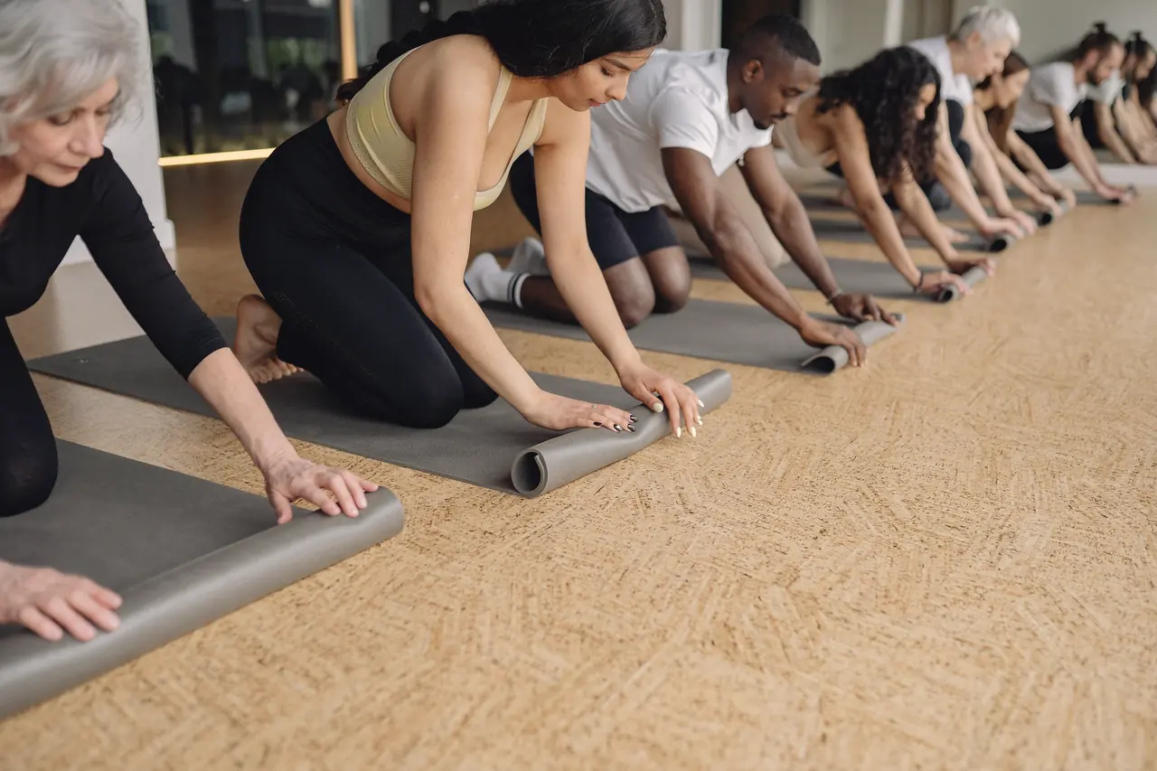 Students of several ages unrolling their mats along the floor in the minutes before class