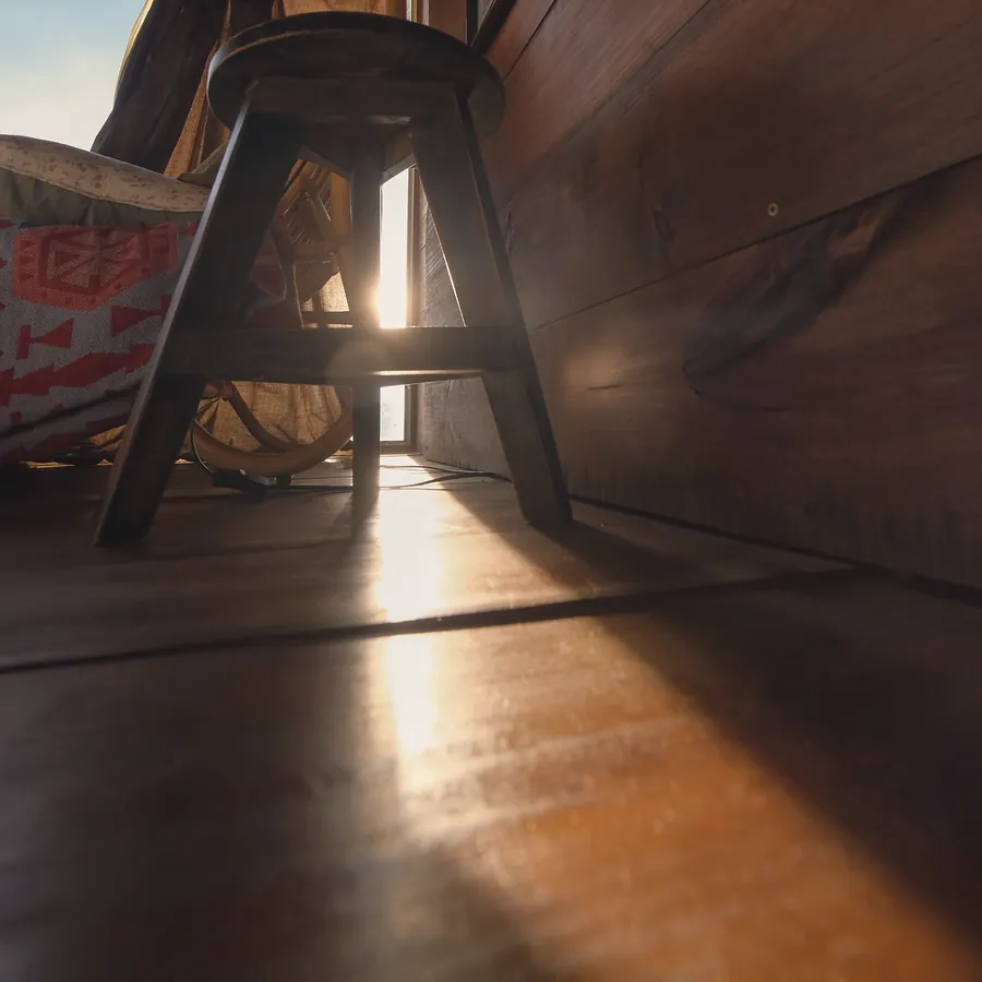 A wooden stool and a band of warm light lying across the floorboards