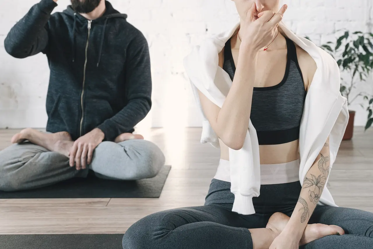 Two students sitting upright, one hand at the ribs, practising a breathing pattern