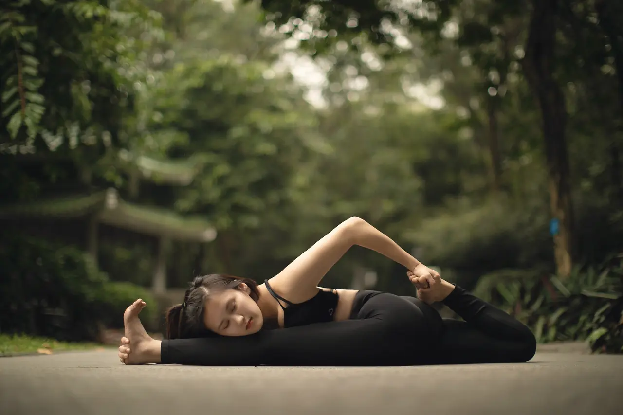 A student settled into a long reclined twist, greenery soft behind her