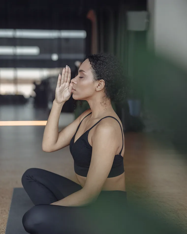 A teacher seated with her hands at her heart, eyes closed, warm light across her shoulder