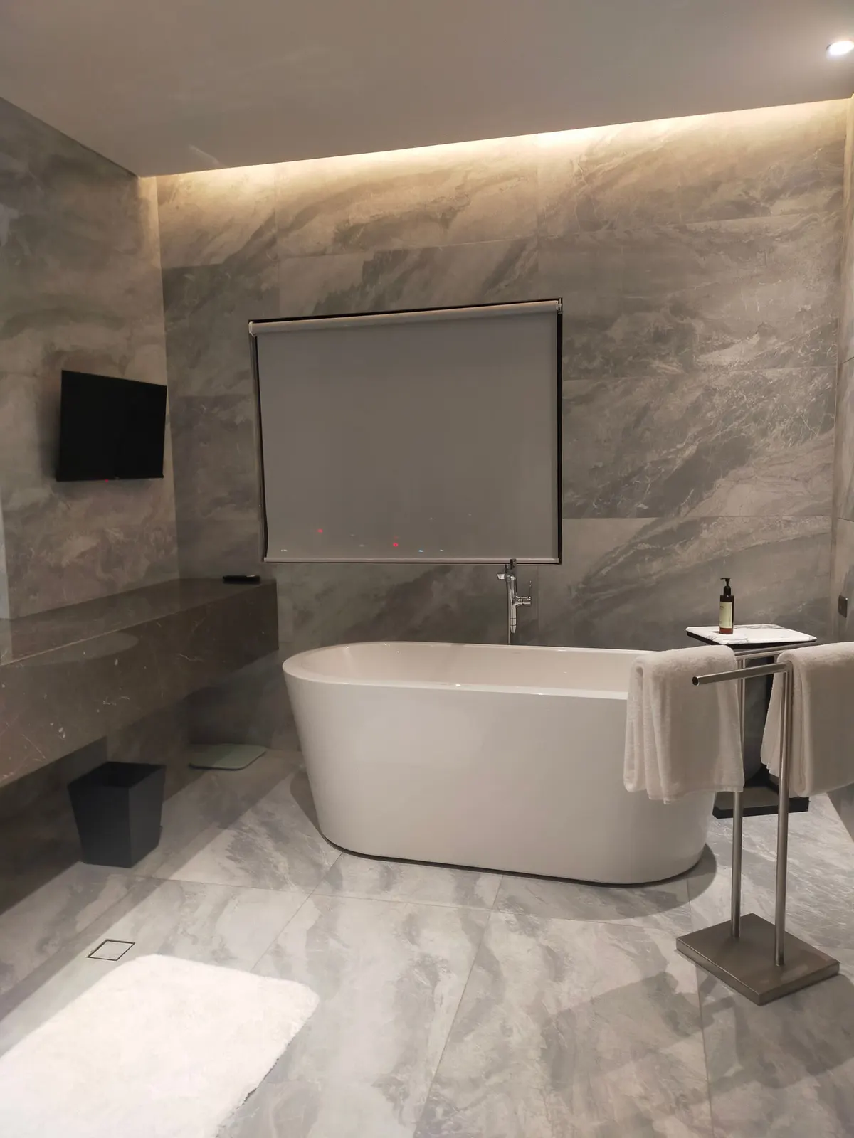 A spa-style bathroom with a freestanding tub set against book-matched marble