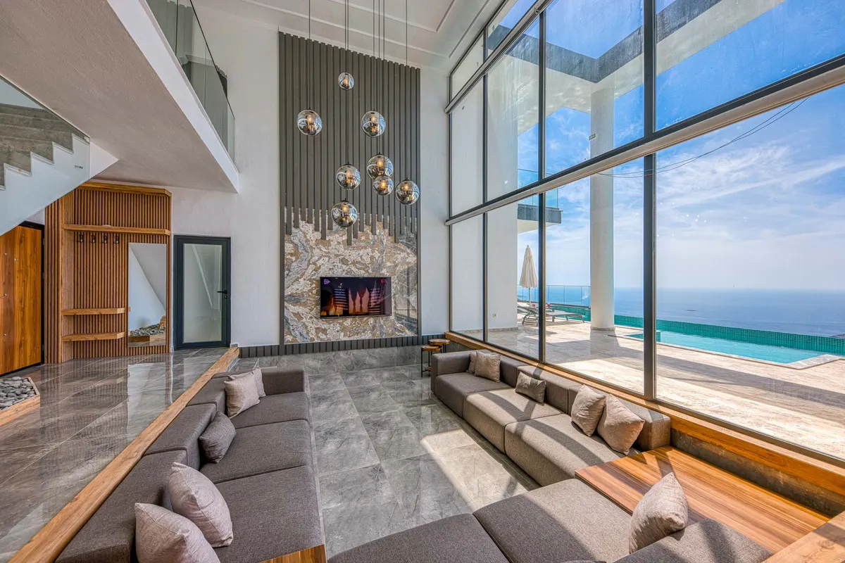 The great room from the stair landing, fireplace and ocean view beyond the pool