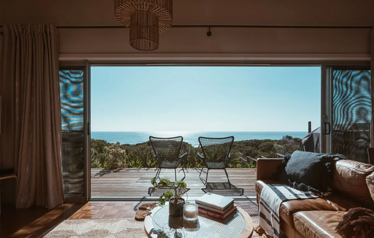 A sitting room opening through sliding glass onto a covered terrace facing the ocean