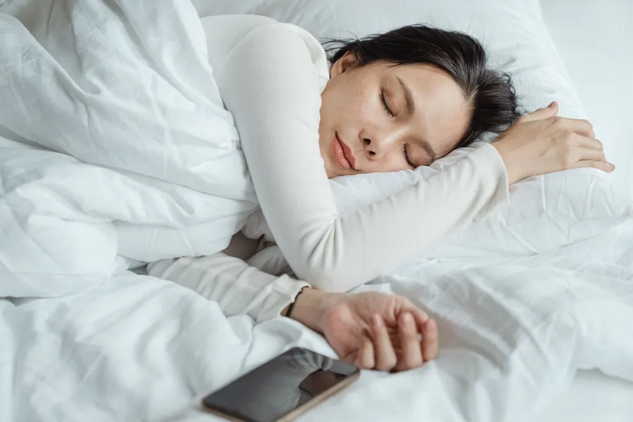 A woman sleeping in bed near a phone