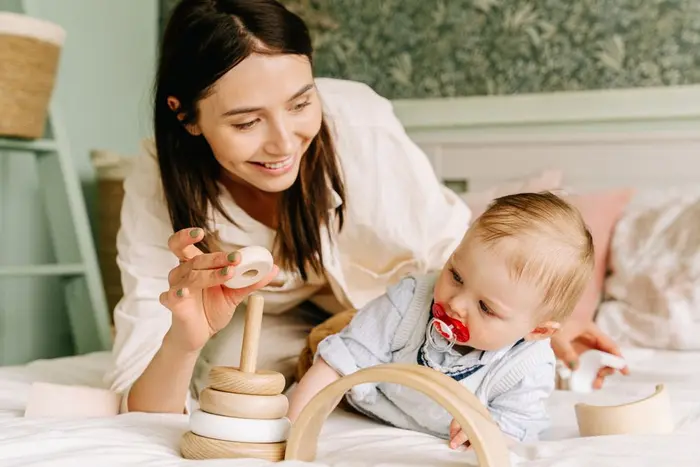 A parent and baby playing together with a wooden toy