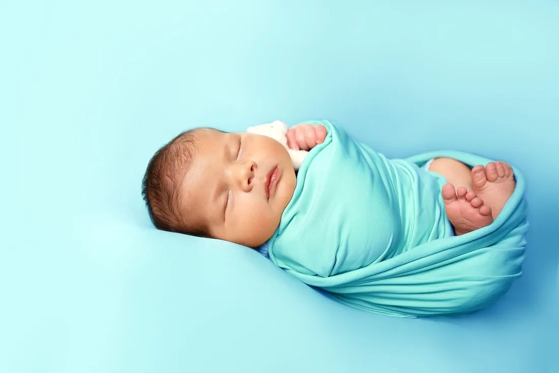A newborn baby wrapped snugly in a soft swaddle