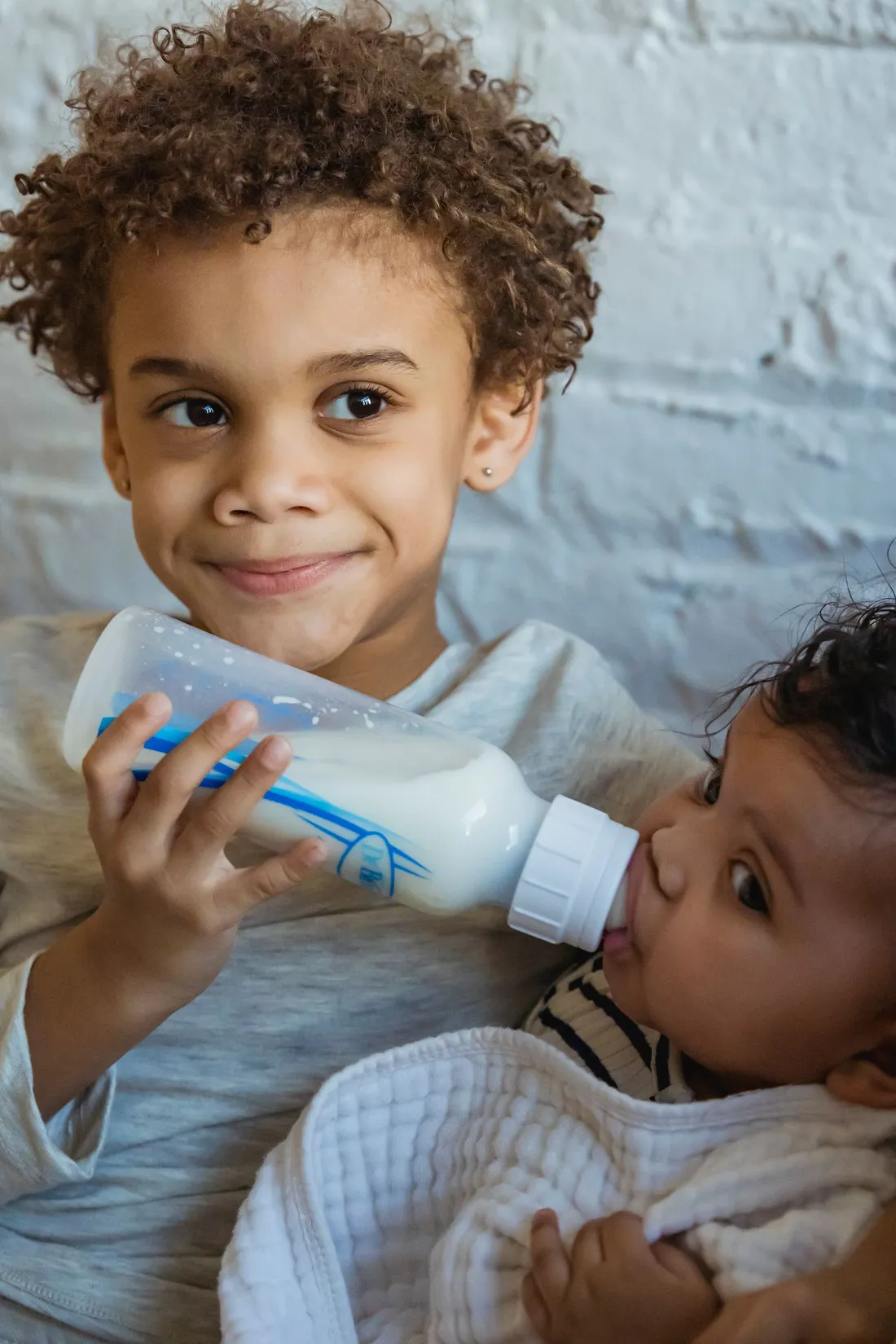 A caregiver feeding a small baby from a bottle