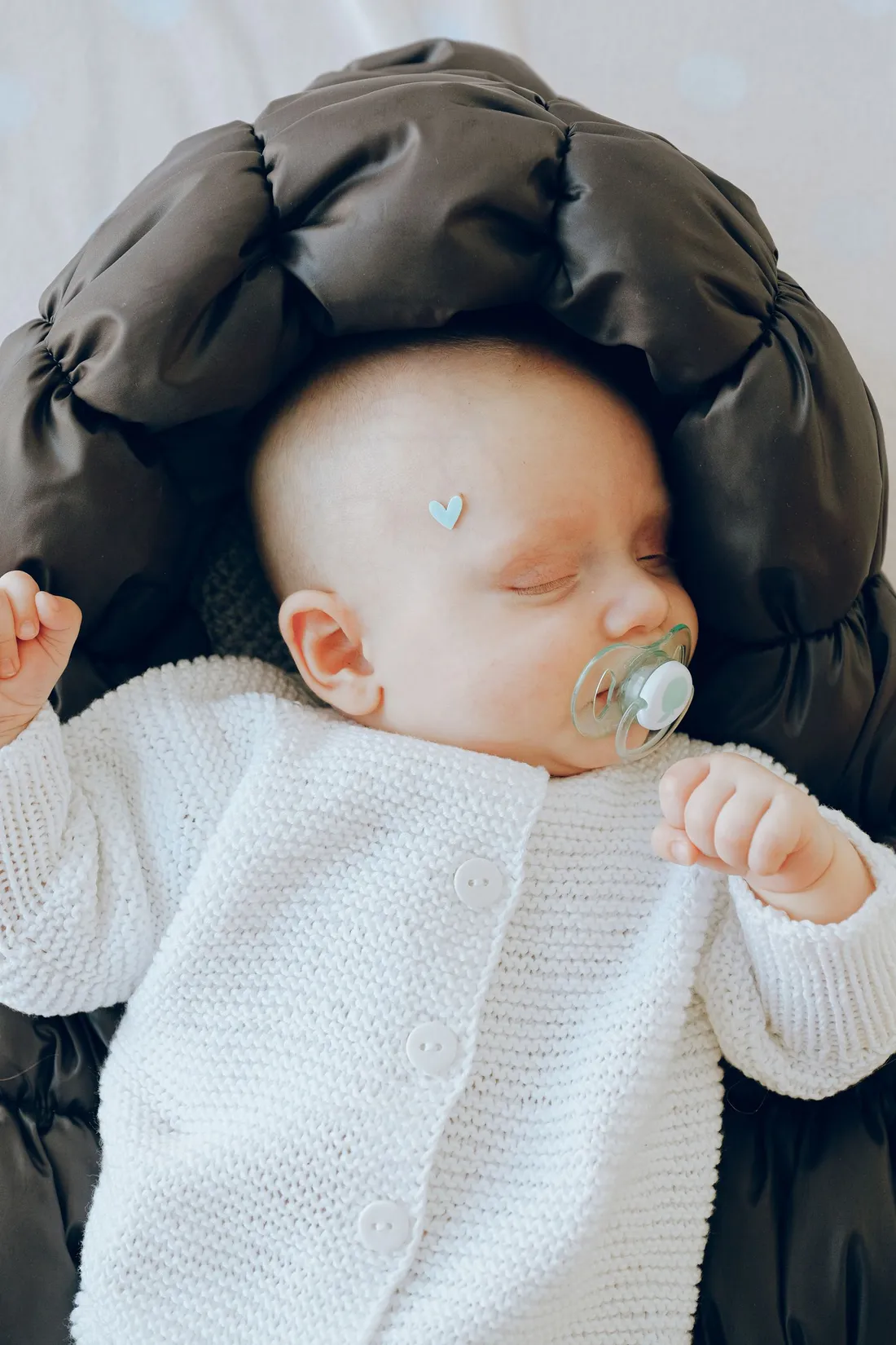 An infant sleeping in a soft bassinet