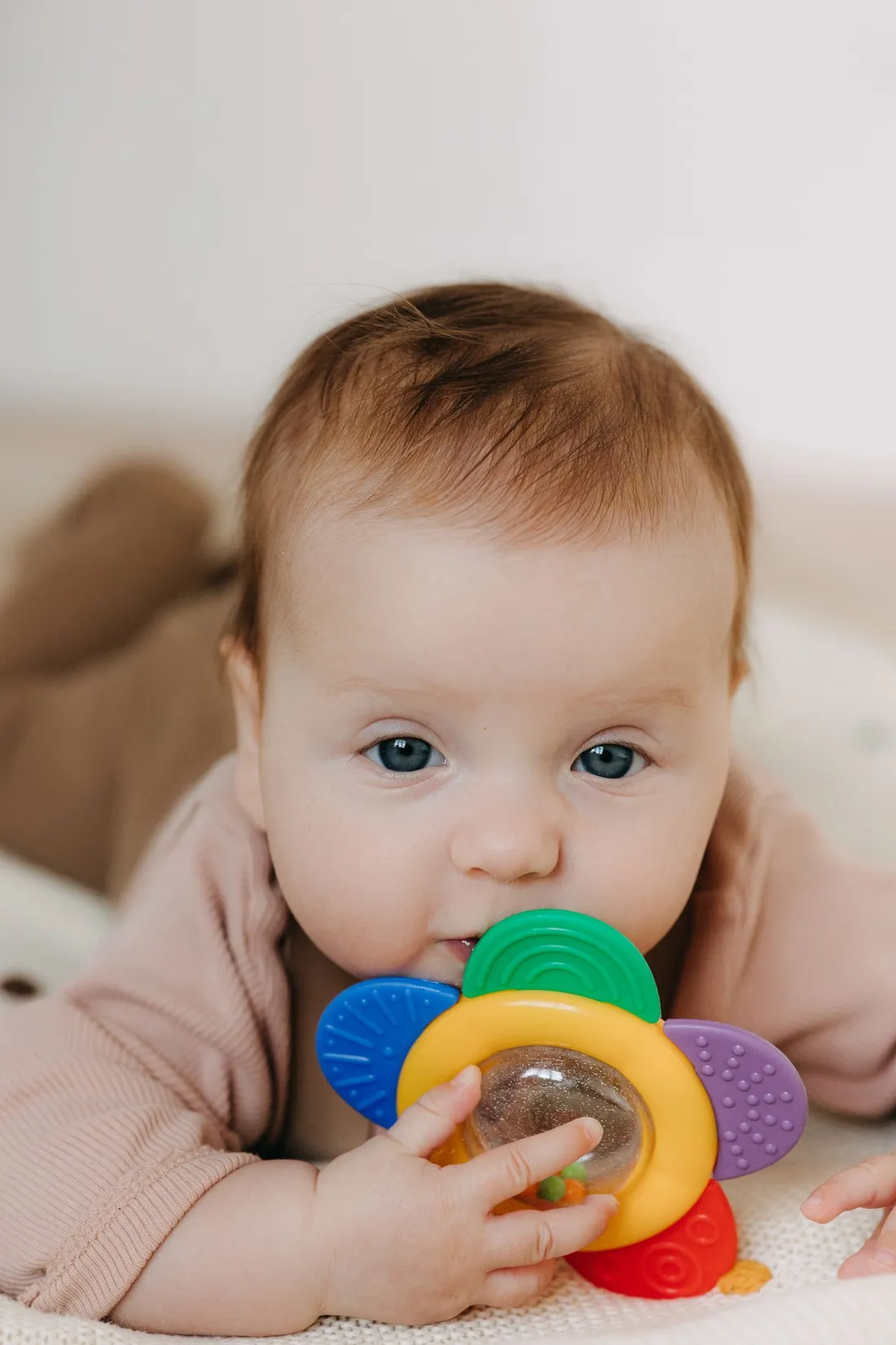 A baby playing with a colourful teething toy