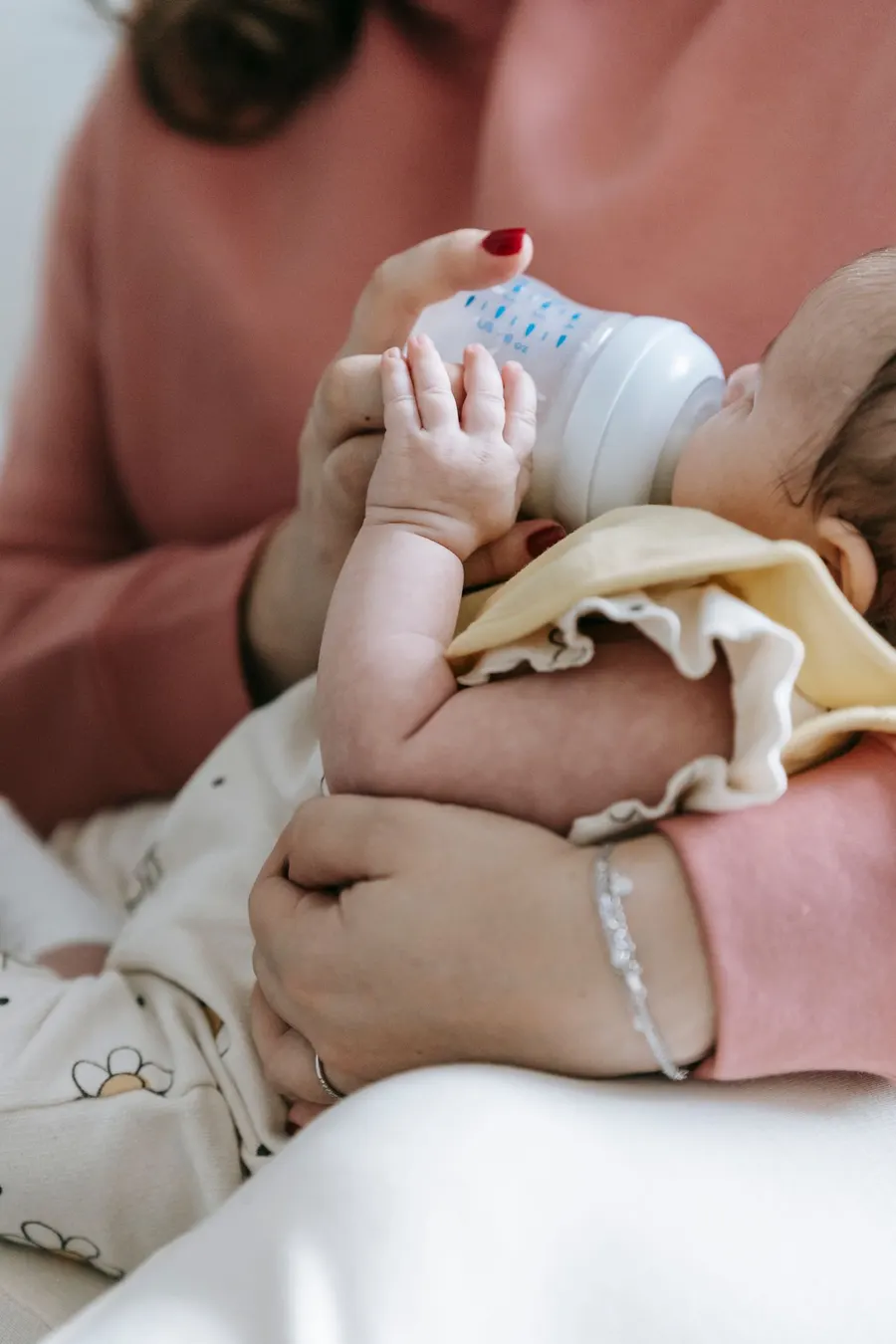 A caregiver feeding a newborn baby