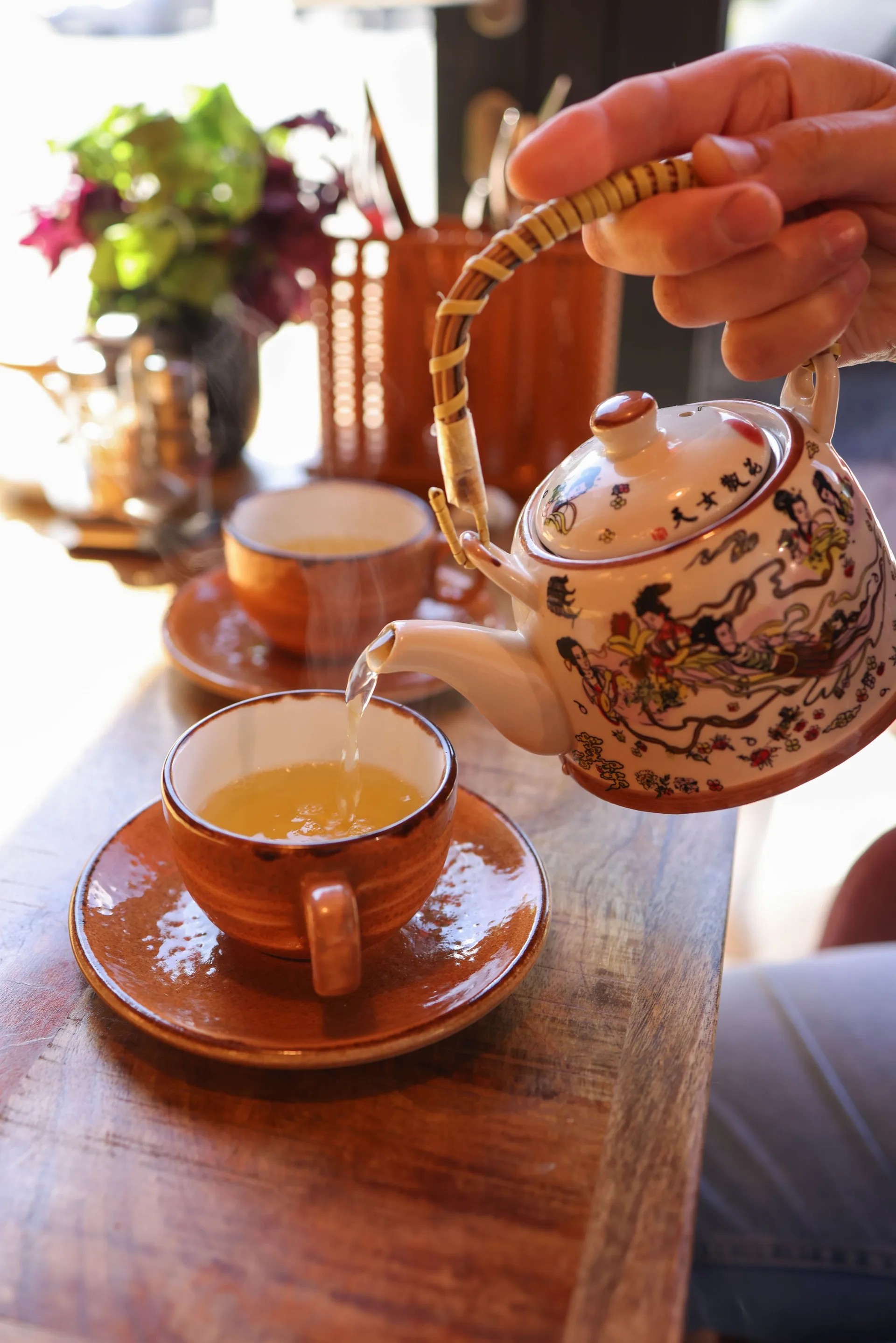 A hand pouring tea from a teapot into a cup