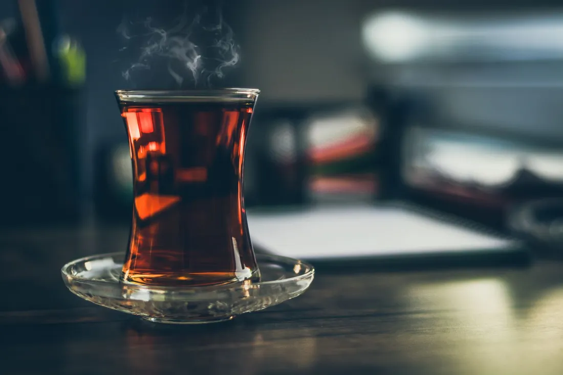 Steaming glass of dark brewed black tea, close up