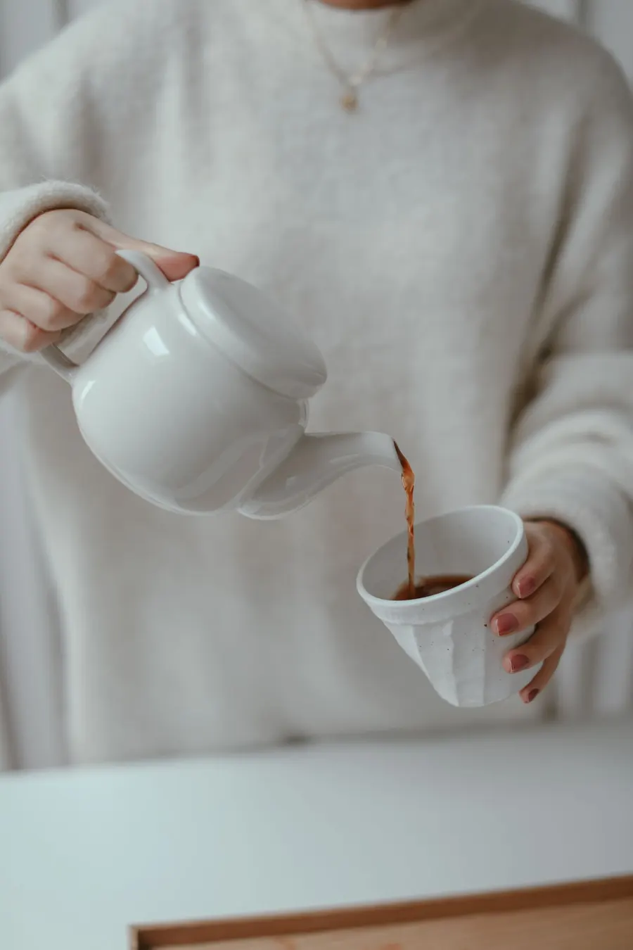 A person holding a teapot, pouring tea