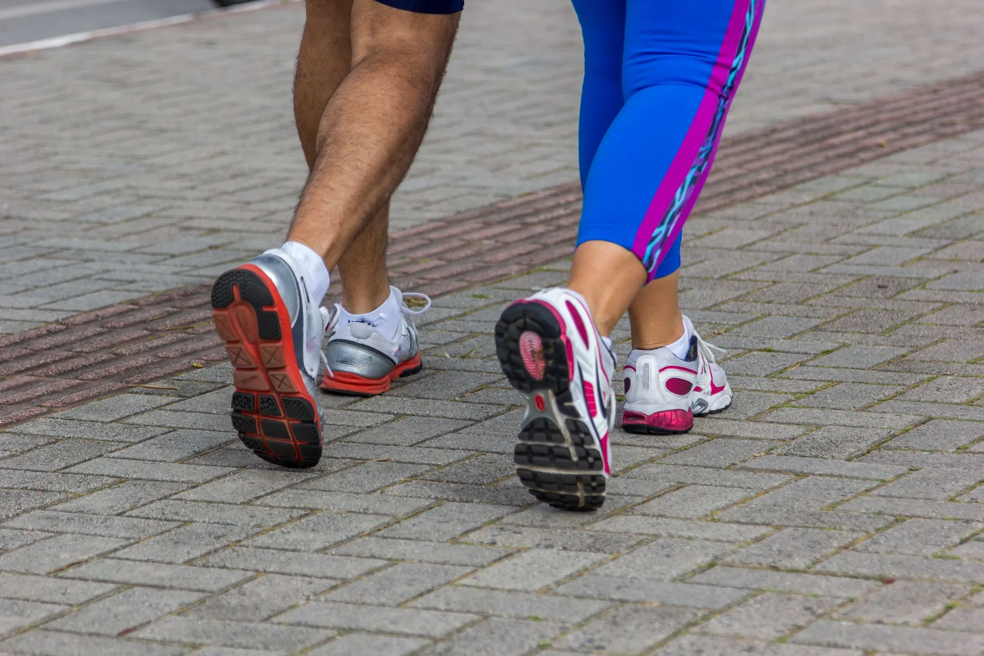 Two runners in motion on a city sidewalk