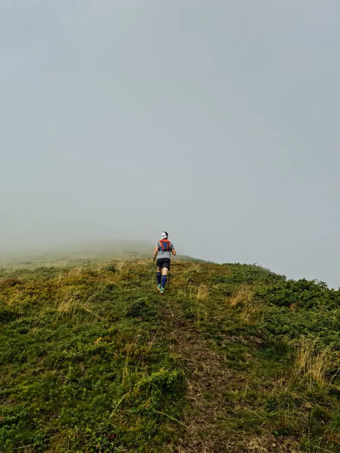 A solo trail runner ascending a foggy hillside